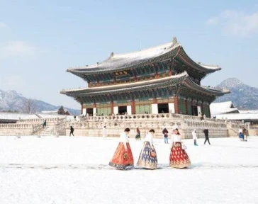 雪中的景福宫和穿韩服的游客。